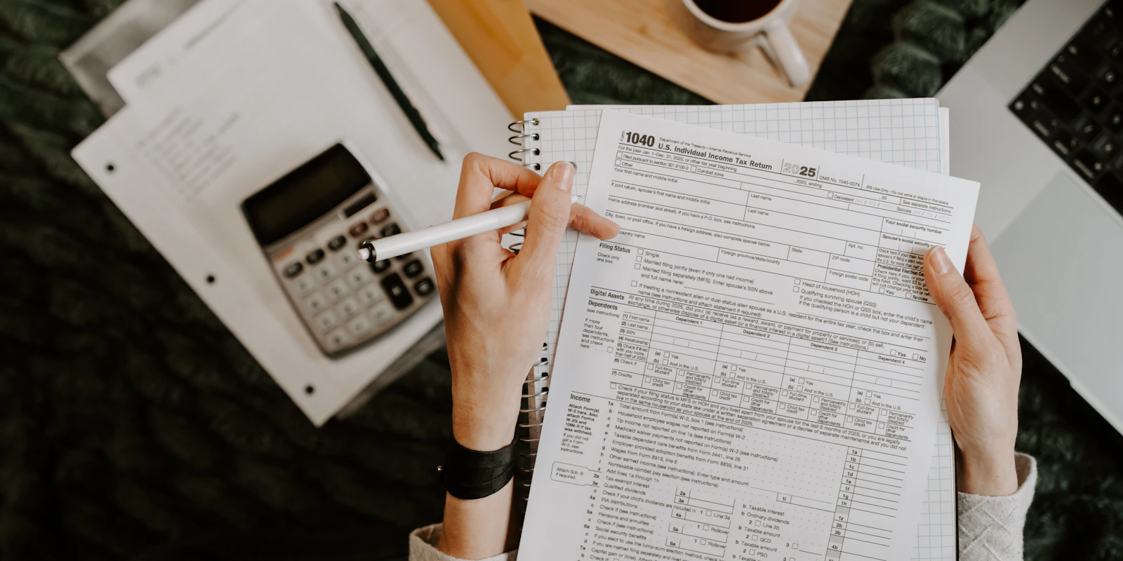 Personne examinant des documents avec une calculatrice et un ordinateur portable